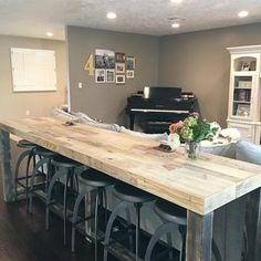 a kitchen island with stools and a piano in the background