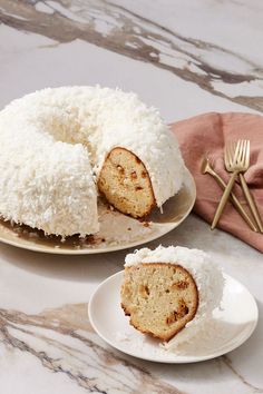 there is a bundt cake with coconut on the plate and another one has a slice cut out