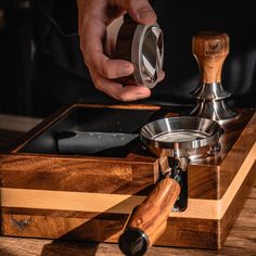 a person holding a grinder in their hand over a wooden box with other items on it