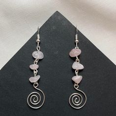 two pairs of earrings with spiral design and pink stones hanging from the earwires