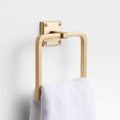 a gold towel rack with two towels hanging on it's sides and a white wall in the background