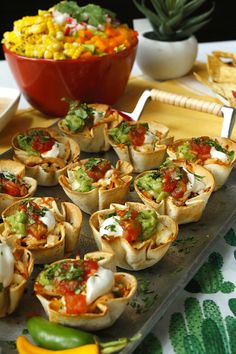 a tray filled with tacos next to a bowl of corn