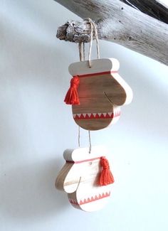 a wooden ornament hanging from a branch with red tassels on it