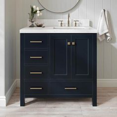 a white sink sitting under a mirror next to a blue cabinet with drawers and pulls