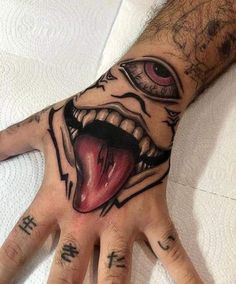 a person's hand with tattoos on it and an evil face painted on the palm