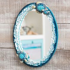 a blue mirror hanging on the side of a wooden wall next to a white dresser