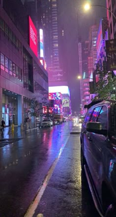 a city street at night with cars parked on the side