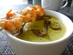 a white bowl filled with soup and shrimp skewers