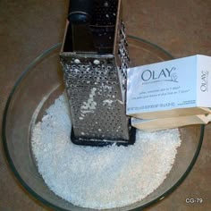 an open cell phone sitting on top of a glass bowl filled with white sand next to a book