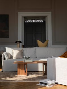 a living room with white couches and pillows on the floor in front of a black door