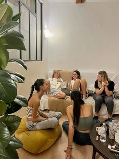 a group of people sitting on top of couches in a living room next to a plant