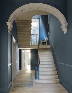 an arched doorway leading to a hallway with blue walls and white carpet on the floor