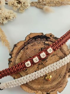 three bracelets with words on them sitting on top of a piece of driftwood