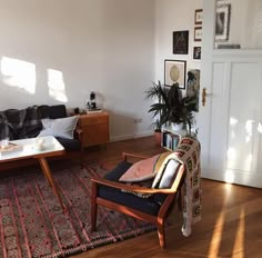 a living room filled with furniture next to a white wall and wooden floored floors