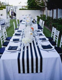 a long table is set with blue and white linens for an outdoor wedding reception