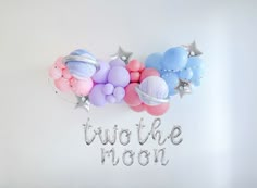 balloons and stars are hanging on the wall with words that spell out two to be moon