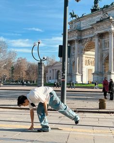 a person bending over on the ground in front of a street light and arch of triumph