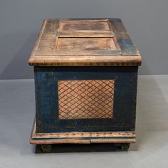 an old wooden box sitting on top of a gray floor next to a white wall