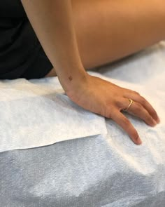 a woman laying on top of a bed with her hand resting on the pillow next to her