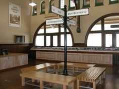 the inside of a train station with benches and tables in front of large arched windows