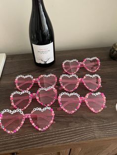 pink heart shaped sunglasses sitting on top of a table next to a bottle of wine