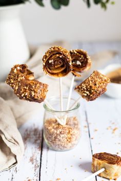 there are several desserts in a glass jar on the table and one is wrapped in paper