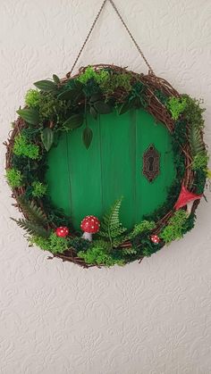 a green door is hanging on the wall with some plants and mushrooms around it,