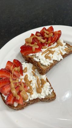 two slices of toast with strawberries and whipped cream on them sitting on a white plate