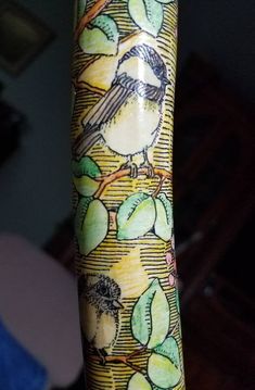 a bird on a tree branch with leaves and berries painted on it's leg