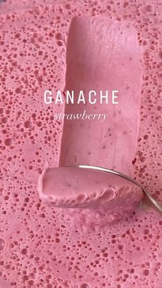 a spoon that is sitting on top of some pink substance with the word ganache in it