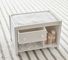 an open drawer on the floor with toiletries in front of it and a striped rug