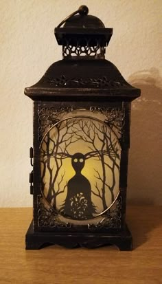 an old fashioned lantern with a silhouette of a person in the woods on it's side