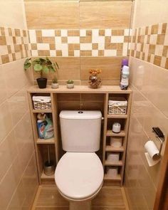 a toilet in a small bathroom with shelves on the wall and tiled walls behind it