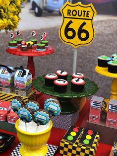 a table topped with cupcakes and cakes next to a sign that says route 66