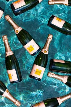 several bottles of champagne sitting in the water together on top of a blue tablecloth