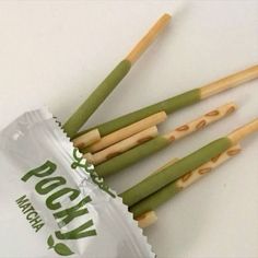 four green and yellow sticks sticking out of a wrapper on top of a white table