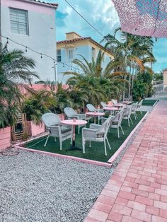 tables and chairs are set up outside on the grass with pink umbrellas hanging over them