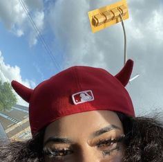 a woman wearing a red devil hat with horns on her head and eyeliners