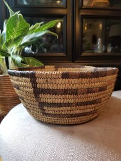 a woven basket sitting on top of a table next to a potted green plant