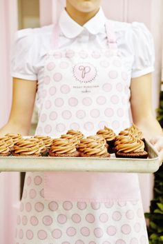 a woman holding a tray with cupcakes on it