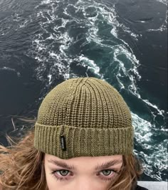 a woman with long hair wearing a green knitted beanie looking at the camera