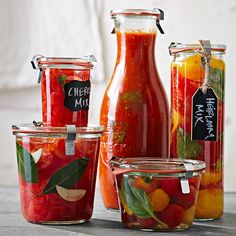 several jars filled with different types of fruit and vegetables next to each other on a table