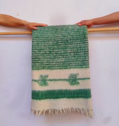 two hands are holding a green and white towel on a wooden stick, while the other hand is pulling it up