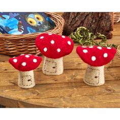 three red mushrooms sitting on top of a wooden table