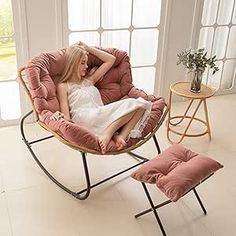 a woman sitting in a pink chair next to a window