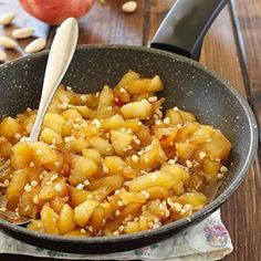 a pan filled with food sitting on top of a wooden table next to an apple