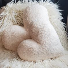 a white fluffy pillow sitting on top of a furry chair cushion with two pillows in the shape of hearts