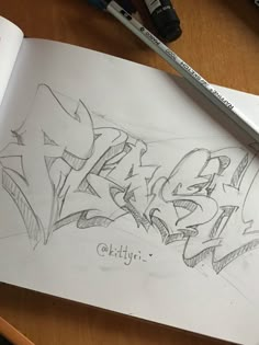 an open book with graffiti written on it next to some markers and pencils,