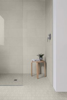 a white tiled bathroom with a small table and plant on the counter next to it