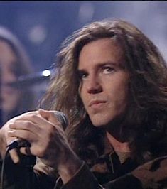 a woman with long hair holding a microphone in her right hand and looking off to the side